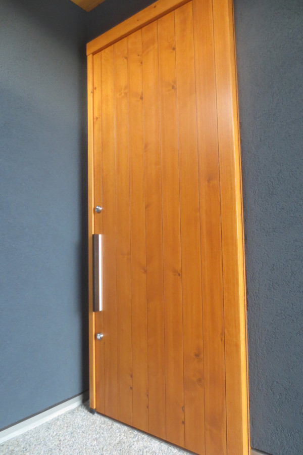 濃色の存在感ある外観に明るい木製の玄関引戸