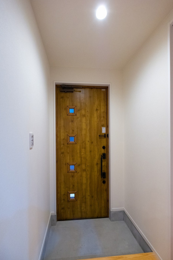 モルタル土間と木目調ドアのナチュラルな玄関ホール